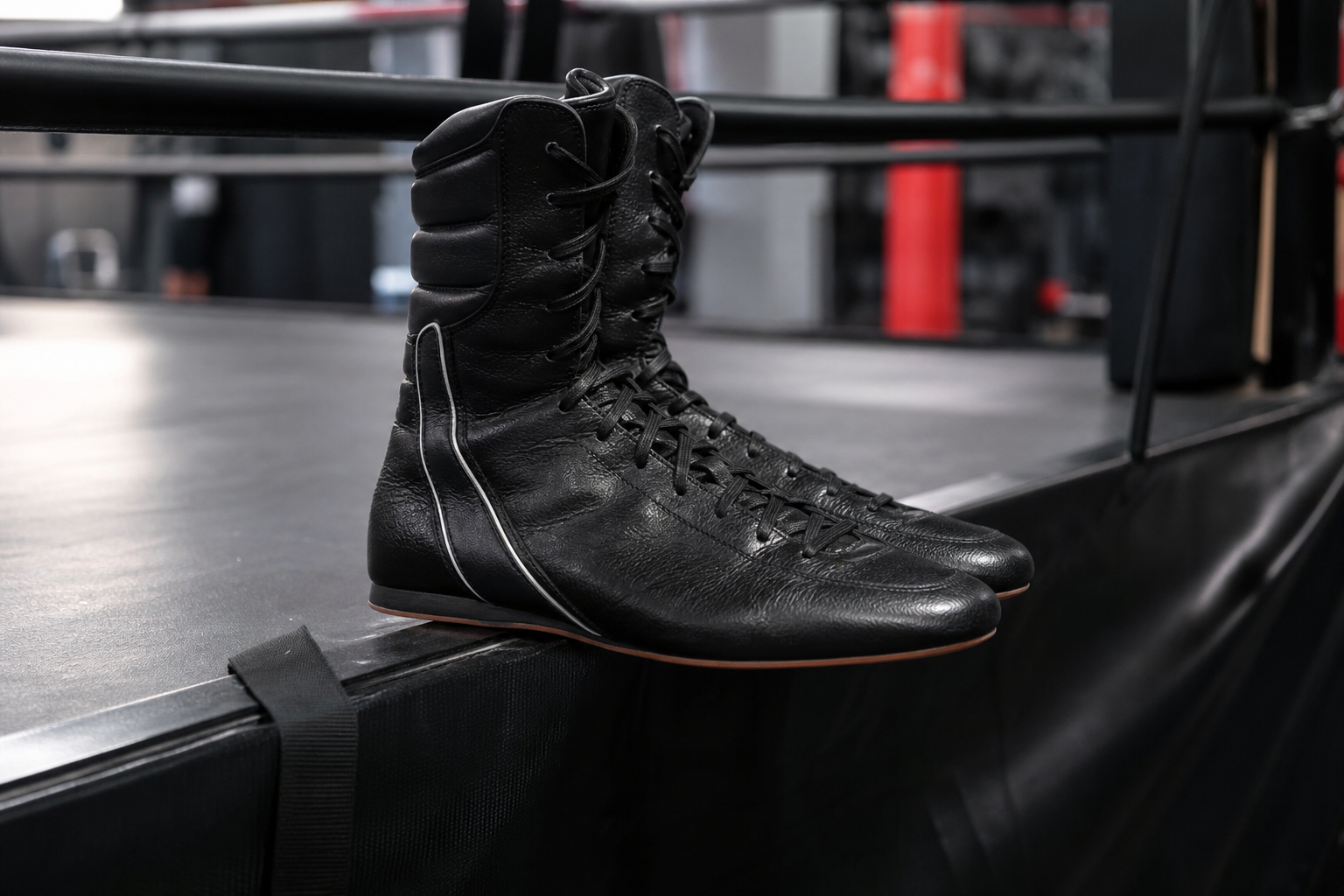 Paire de chaussures de boxe montantes en cuir souple posée au bord d'un ring