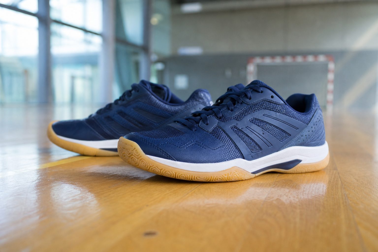Chaussures de handball basses à semelle en gomme claire posées sur un parquet de salle de sport