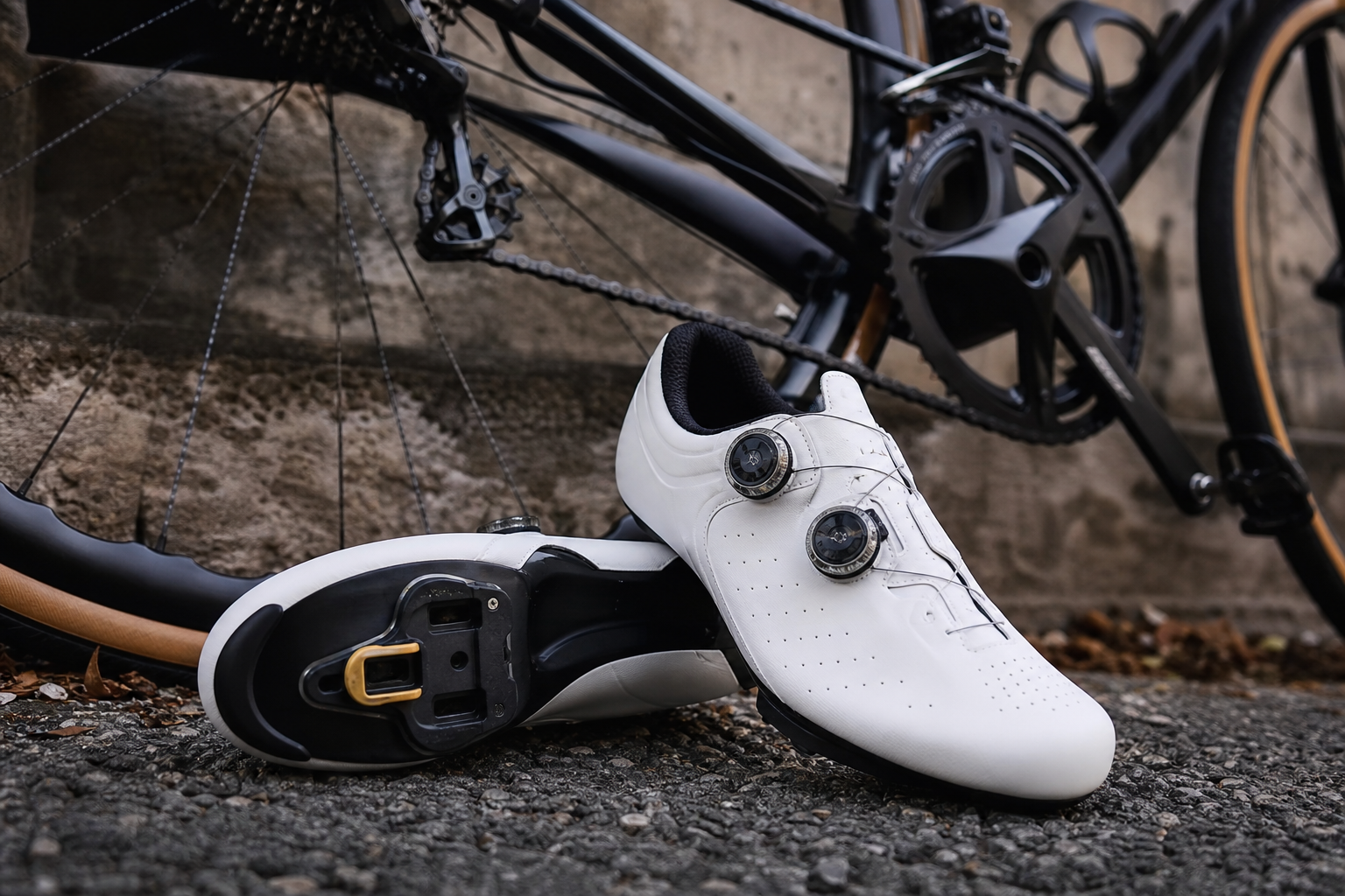 Chaussures de cyclisme à cales posées à côté d'un vélo, gros plan sur la semelle rigide